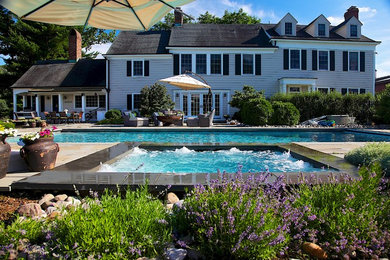 Ejemplo de piscinas y jacuzzis alargados clásicos de tamaño medio rectangulares en patio trasero con adoquines de piedra natural