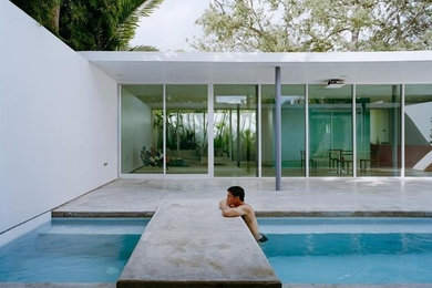 Ejemplo de casa de la piscina y piscina rectangular en patio con losas de hormigón