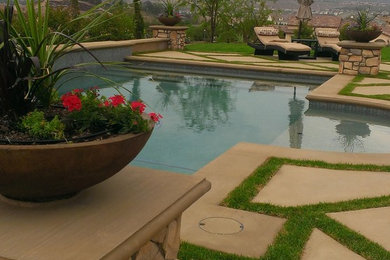 Modelo de piscina mediterránea grande a medida en patio trasero con adoquines de piedra natural