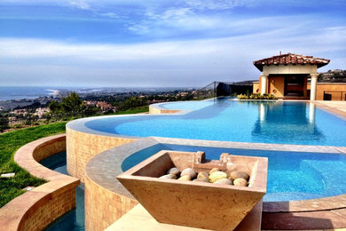 Large tuscan backyard tile and custom-shaped infinity hot tub photo in Orange County