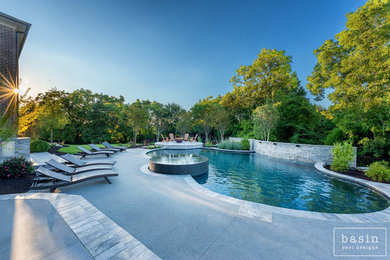 Esempio di una grande piscina naturale mediterranea personalizzata dietro casa con una vasca idromassaggio e pavimentazioni in cemento