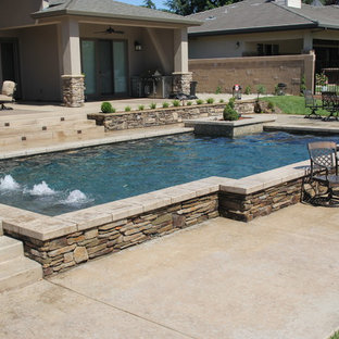 Ejemplo de piscina con fuente elevada, actual, de tamaño medio, rectangular, en patio trasero, con losas de hormigón