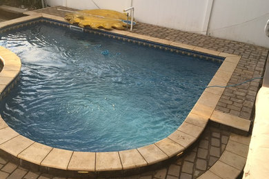 Pool - backyard brick and custom-shaped pool idea in New York