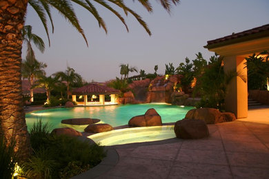 Large island style backyard stamped concrete and custom-shaped pool fountain photo in Orange County