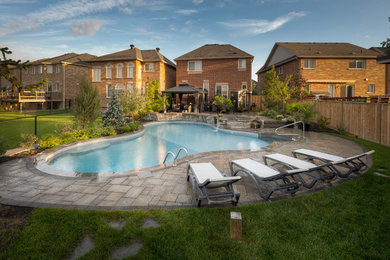 Example of a large classic backyard stone and custom-shaped natural hot tub design in Toronto
