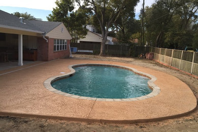 Large elegant backyard stamped concrete and custom-shaped natural pool photo in Miami