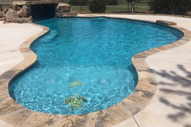 Example of a large island style backyard custom-shaped natural pool design in Oklahoma City