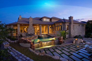 Example of a huge trendy backyard stone and custom-shaped infinity pool fountain design in Austin