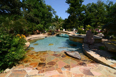 Idée de décoration pour une grande piscine naturelle et arrière tradition sur mesure avec des pavés en pierre naturelle et un bain bouillonnant.