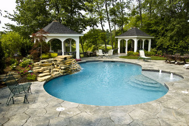 Ejemplo de piscina natural de tamaño medio a medida en patio trasero con suelo de hormigón estampado