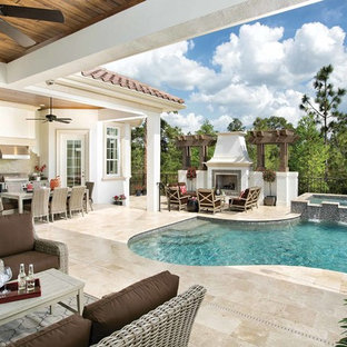Photo of a mid-sized mediterranean backyard custom-shaped pool in Orlando with a water feature and natural stone pavers.
