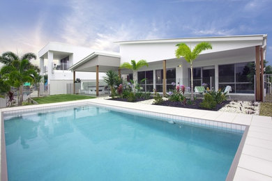 Diseño de piscina alargada actual grande rectangular en patio trasero con suelo de baldosas