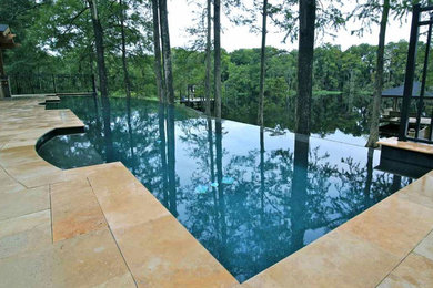 Foto di una piscina a sfioro infinito minimalista rettangolare di medie dimensioni e dietro casa con piastrelle