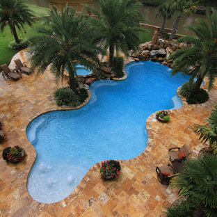 Tropical backyard custom-shaped pool in New Orleans with a water feature.