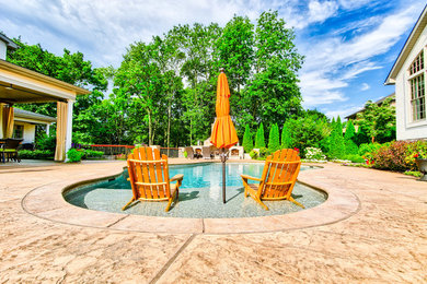 Imagen de piscina natural tradicional renovada de tamaño medio a medida en patio trasero con suelo de hormigón estampado
