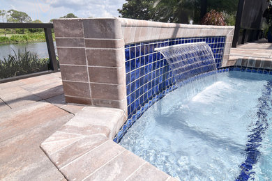Modelo de piscina actual de tamaño medio a medida en patio trasero con adoquines de hormigón