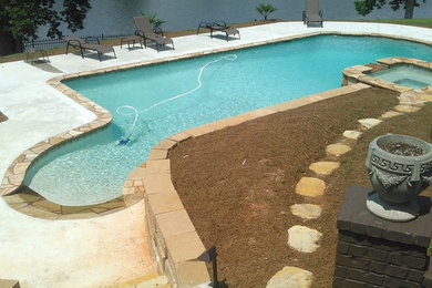 Modelo de piscinas y jacuzzis alargados tradicionales de tamaño medio rectangulares en patio trasero con adoquines de piedra natural