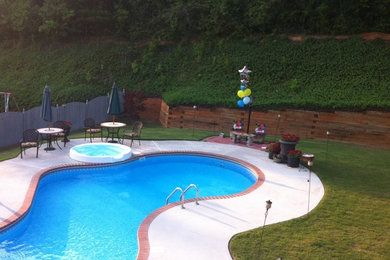 Diseño de piscina clásica grande a medida en patio trasero con losas de hormigón