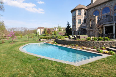 Large elegant backyard custom-shaped and stamped concrete lap pool photo in Philadelphia