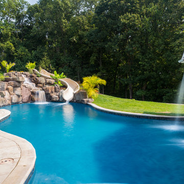 Custom pool with rock waterfalls, water slide & swim up pool bar.