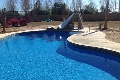 Inspiration for a large timeless backyard stone and custom-shaped natural water slide remodel in Miami