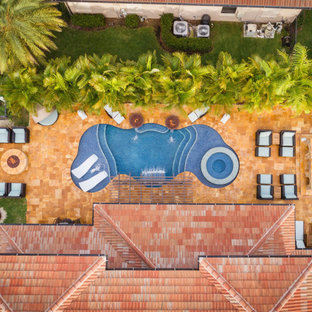Mid-sized backyard custom-shaped pool in Miami with a water feature and natural stone pavers.