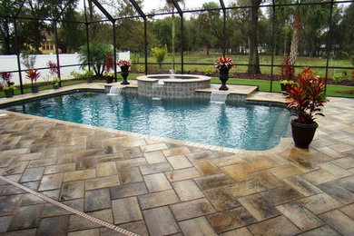 Imagen de piscina grande a medida en patio trasero con adoquines de piedra natural
