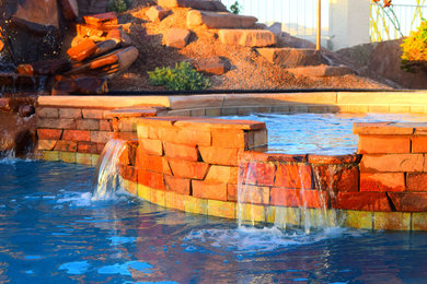 Diseño de piscina con fuente grande a medida en patio trasero con adoquines de hormigón