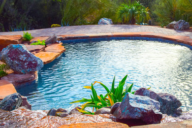Foto de piscinas y jacuzzis grandes a medida en patio trasero con adoquines de hormigón