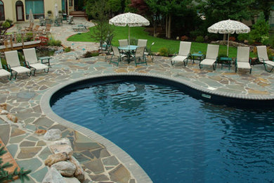 Imagen de piscina con fuente alargada grande a medida en patio trasero con adoquines de piedra natural