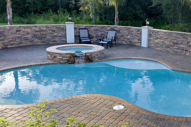 Ispirazione per una piscina naturale minimal personalizzata di medie dimensioni e dietro casa con una vasca idromassaggio e pavimentazioni in cemento