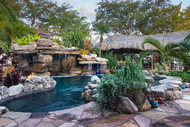 Inspiration for a huge tropical backyard stone and custom-shaped natural pool fountain remodel in Tampa