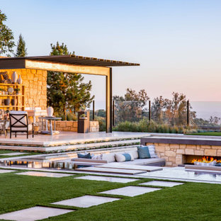 Immagine di un'ampia piscina a sfioro infinito minimalista personalizzata dietro casa con pavimentazioni in pietra naturale