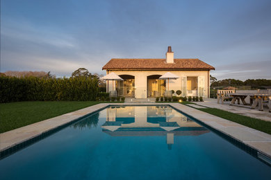 Ejemplo de piscina campestre de tamaño medio rectangular en patio trasero con adoquines de piedra natural