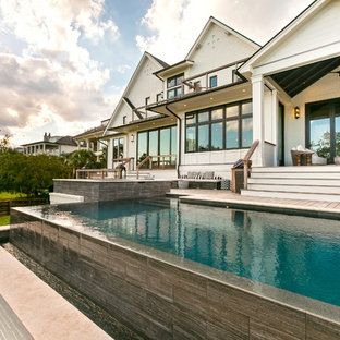 Immagine di una grande piscina a sfioro infinito chic rettangolare dietro casa con una vasca idromassaggio e pedane