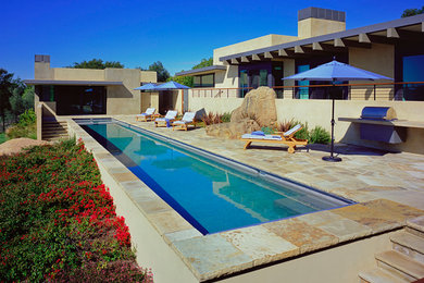 Foto de piscina alargada contemporánea grande rectangular en patio trasero con adoquines de piedra natural