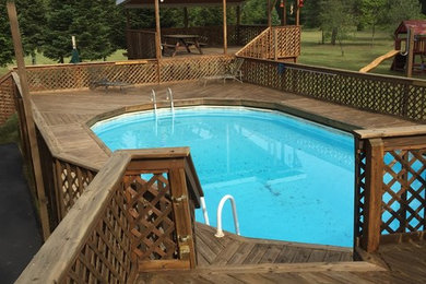 Inspiration for a large side yard custom-shaped aboveground pool remodel in Grand Rapids with decking