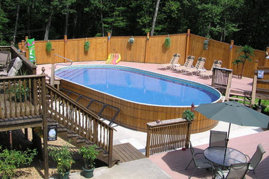 На фото: наземный бассейн на заднем дворе в средиземноморском стиле с покрытием из бетонных плит с