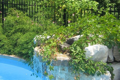 Modelo de piscina con fuente natural clásica grande a medida en patio trasero con adoquines de piedra natural