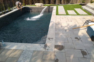 Foto de piscina con fuente contemporánea pequeña rectangular en patio trasero con adoquines de piedra natural