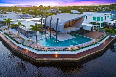 Inspiration for an expansive contemporary back custom shaped infinity swimming pool in Sunshine Coast with tiled flooring.