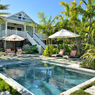 Immagine di una piscina tropicale personalizzata con pavimentazioni in cemento