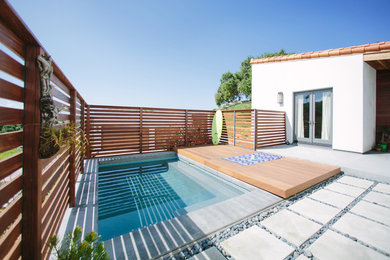Modelo de piscina actual rectangular en patio trasero con adoquines de hormigón