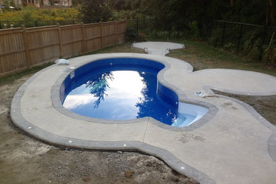 Imagen de piscina tradicional pequeña tipo riñón en patio trasero con suelo de hormigón estampado