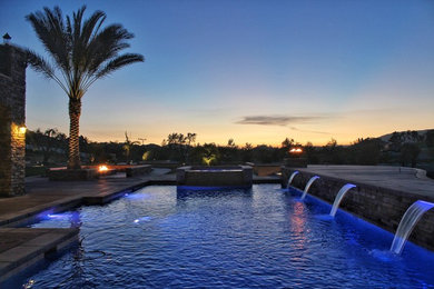 Imagen de piscina con tobogán alargada mediterránea grande rectangular en patio trasero con losas de hormigón