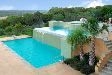 На фото: огромный бассейн-инфинити произвольной формы на заднем дворе в стиле модернизм с фонтаном и покрытием из бетонных плит с