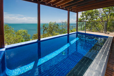 Foto de piscina alargada exótica de tamaño medio rectangular en patio trasero con entablado