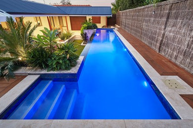 Diseño de piscina con fuente alargada minimalista grande rectangular en patio trasero con adoquines de piedra natural