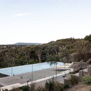 Design ideas for a large beach style backyard rectangular infinity pool in Melbourne with decking.