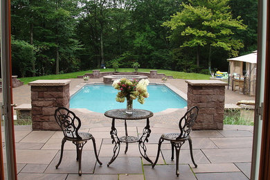 Design ideas for a large classic back custom shaped lengths hot tub in Bridgeport with natural stone paving.